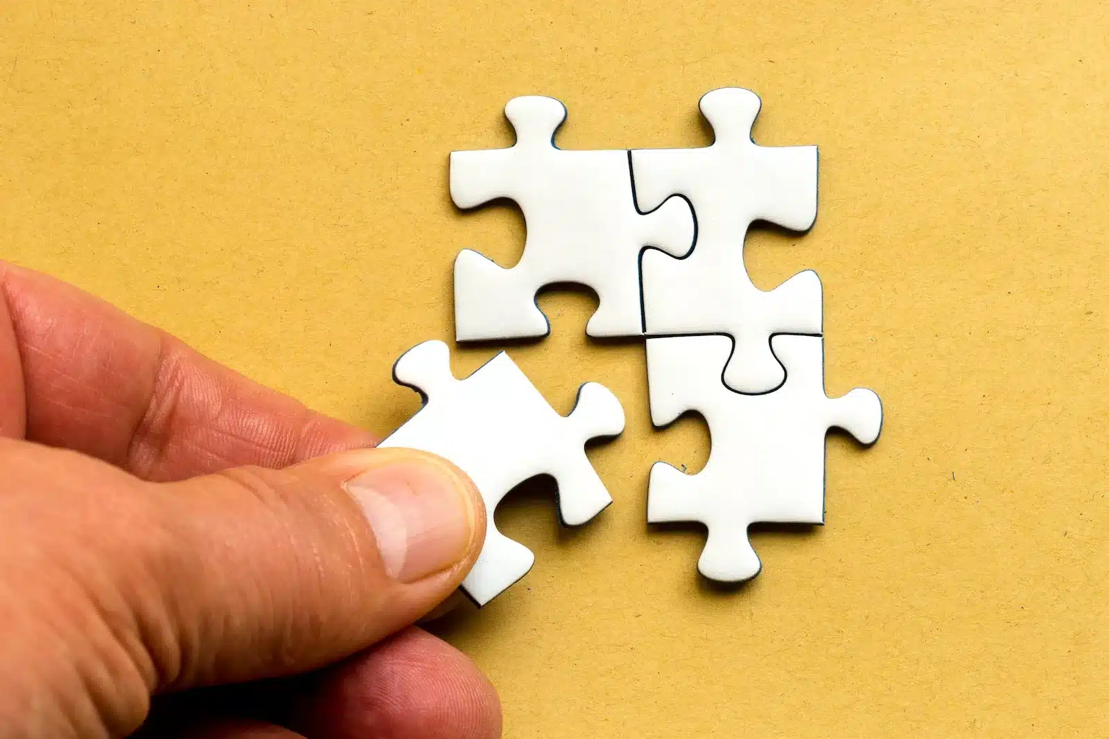 A hand adding a piece to a puzzle, symbolizing the concept of adding value to an organization.