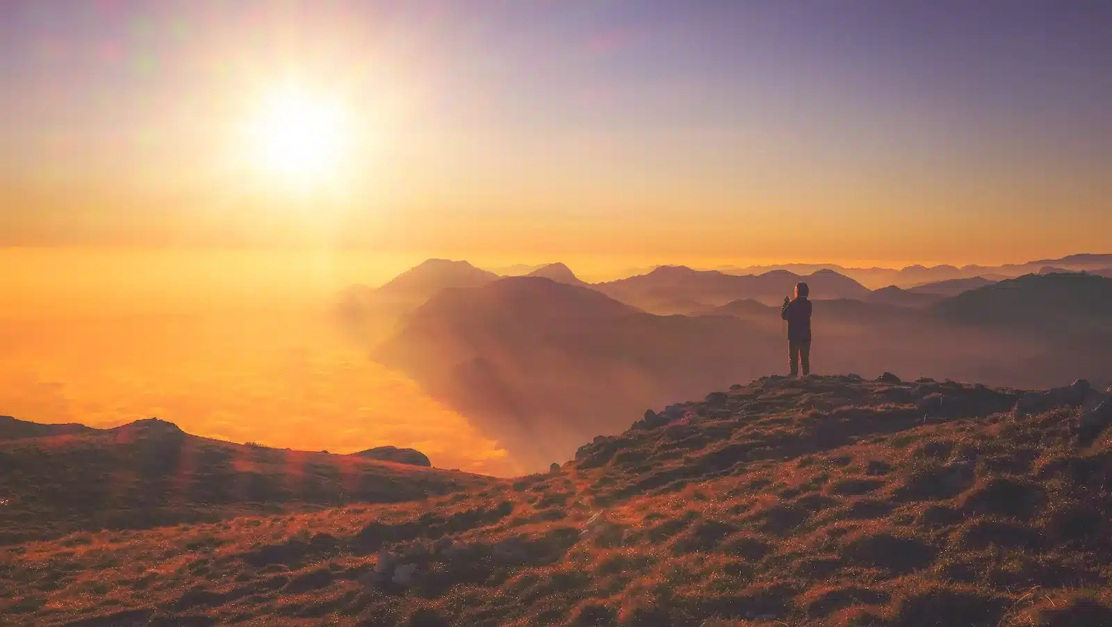 A person standing on a mountain peak, looking out at the horizon, symbolizing the conclusion of the journey through the Baarda Model.
